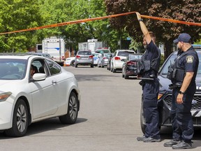 A police officer allows a neighbour to leave the security perimeter near a home on Place du Comoran where a man was killed during a home invasion in Laval May 24, 2022.