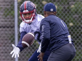 Running-back Jordan Scarlett takes a toss from head coach Khari Jones during Montreal Alouettes training camp practice in Trois-Rivières on May 26, 2022.