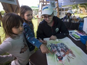 Éloise Bundaru (centre) and sister Ariane look on as Diane Heaganton works on a painting Saturday at Meades Park as part of the Kirkland Art Festival, a new cultural event providing participants with a unique opportunity to observe visual artists create original works of art in real time.