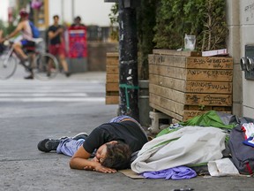 A man sleeps on the sidewalk in Montreal's Milton Park neighbourhood in 2021.