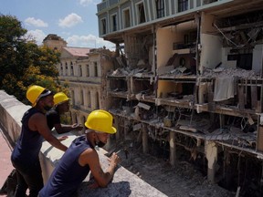 Workers look at the Saratoga Hotel a day after it suffered an explosion, in Havana, Cuba, on Saturday, May 7, 2022.