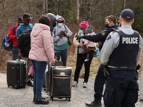 Asylum seekers talk to a police officer as they cross into Canada from the U.S. near a checkpoint on Roxham Rd. in April 2022.