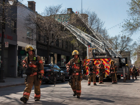 Firefighters walk away from the scene of a fire just north of the intersection of St-Laurent Blvd. and Prince Arthur St. that went from a one-alarm fire to a four-alarm fire very quickly on Saturday, May 7, 2022, in Montreal. No injuries were reported.