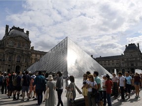 Tourists queue outside the Pyramid prior to entering the Louvre museum in Paris.
