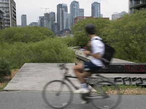 A cyclist gets a look at the downtown skyline near Allee des Vraquiers in Griffintown on Monday May 16, 2022.