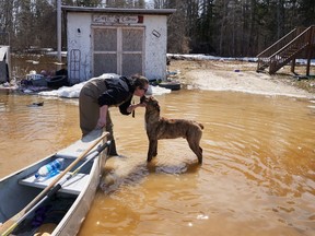 President and founder of Save A Dog Network, Katie Powell gets a kiss from a dog after bringing bags of dog food by canoe to stranded homes during flooding in Peguis First Nation, Man., Wednesday, May 4, 2022. Dozens of experts advising the government on the best way to adapt to the reality of climate change say we need to do more to prepare infrastructure for the threats of extreme weather and get faster help to Canadians when their lives and livelihoods are threatened by floods, fires and major storms.