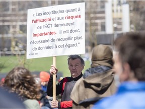 A man holds up a sign during a rally against electroshock treatment in Montreal, Saturday, May 7, 2022.