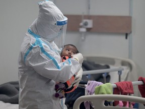 A health worker wearing a Personal Protective Equipment (PPE) suit comforts a child infected with COVID-19 inside a ward at the Commonwealth games (CWG) village sports complex, temporarily converted into COVID-19 care centre, in New Delhi on Jan. 5, 2022.