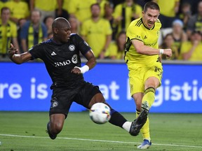 Nashville SC midfielder Alex Muyl, right, scores against CF Montréal defender Kamal Miller during the first half at Geodis Park Wednesday night.