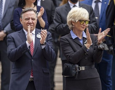 Quebec Premier François Legault and wife Isabelle Brais clap as the hearse carrying Guy Lafleur's coffin passes Mary Queen of the World Cathedral after his funeral in Montreal Tuesday, May 3, 2022.