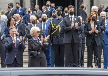 Montreal Mayor Valérie Plante, rear left, Quebec Premier François Legault and wife Isabelle Brais, bottom left, and Prime Minister Justin Trudeau and wife Sophie Grégoire clap as the hearse carrying Guy Lafleur's coffin passes Mary Queen of the World Cathedral after his funeral in Montreal Tuesday, May 3, 2022.