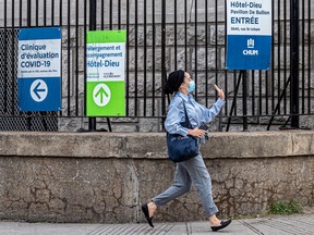 A woman races for a bus past COVID-19 testing signs at Hotel-Dieu in Montreal on Thursday May 26, 2022. Dave Sidaway / Montreal Gazette