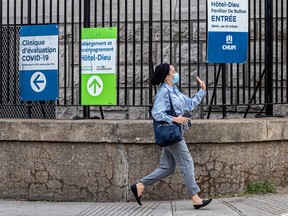 A woman races for a bus past COVID-19 testing signs at Hotel-Dieu in Montreal on Thursday May 26, 2022.