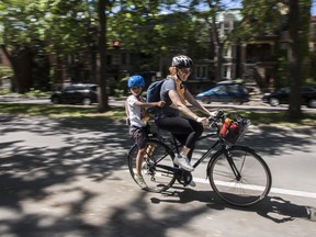 A woman and a youngster leave the Lafontaine Park area during the start of the Tour de l'Île in Montreal Sunday, June 5, 2022.
