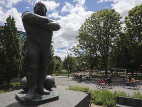 People ride past the statue of Quebec strongman Louis Cyr in the St. Henri area of Montreal as they took part in the Tour de l'Île in Montreal Sunday, June 5, 2022.