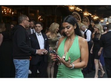 Amanda Rodrigues looks at her phone as she waits for her best friend, boxer Jean Pascal at the Grand Prix Party at the Ritz-Carlton Hotel in Montreal Friday, June 17, 2022.
