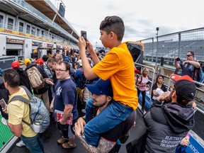 11-year-old Samuel David gets a lift from father Juan David, from Colombia, during the Canadian Grand Prix Pit Lane Walk at Circuit Gilles-Villeneuve in Montreal on June 16, 2022.