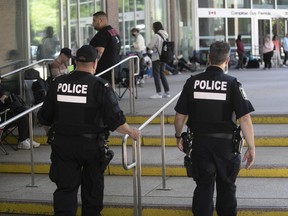 De politie van Montreal patrouilleert aan de buitenkant van Complexe Guy Favreau, waar mensen geduldig wachten op toegang bij het paspoortkantoor op 20 juni 2022.