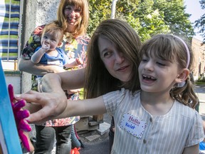 Violet Richardson hand paints with the help of West End Daycare executive director Diana Tosi, while mother Daniela Fietta, community board of directors member, holds August Richardson, during the 75 anniversary party of the daycare on Monday.