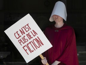 Dressed in a fictional character of the novel Handmaid's Tale, a protester takes part in a pro-choice protest outside Palais de Justice on Sunday June 26, 2022. The protest was in response to the U.S. Supreme Court overturning Roe V. Wade on Friday.