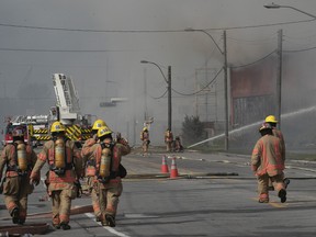 Montreal firefighters walk to relieve their co-workers at the scene of five-alarm blaze at a former recycling centre on Sunday, June 26, 2022.