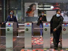 Mask-wearing transit users pass through turnstiles at Guy-Concordia métro station on April 7, 2021.