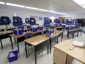 blue chairs are stacked on long desks in an empty classroom