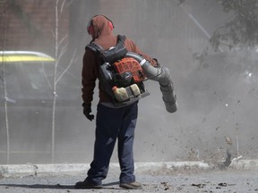 A landscaping crew creates a huge cloud of dirt and debris as they use gas powered leaf blowers to clean the Atwater Market parking lot in 2020.