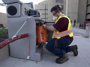 Student Patrick D'Aoust places a wastewater collection container inside a pump station used to collect wastewater samples that are screened for COVID-19 at the University of Ottawa campus on April 8, 2021 in Ottawa. Quebec has been screening wastewater for COVID-19 in Quebec City and the Montreal area since late March, but only began releasing the data Wednesday.