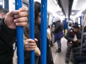 Commuters hold the hand rail in a subway in Montreal on Friday, March 13, 2020.