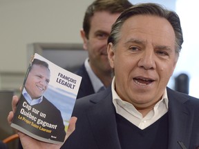 Then-CAQ Leader François Legault holds up his book outlining his dream of a Quebec Silicon Valley during a campaign stop in Trois-Rivières on Monday March 10, 2014.