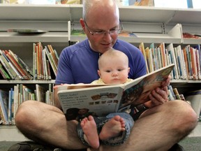 A man reads to a baby in a library.
