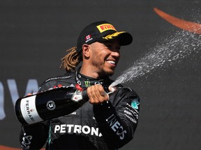 Mercedes’ Lewis Hamilton celebrates on the podium at Circuit Gilles-Villeneuve with sparkling wine after finishing third in the race Sunday.