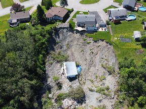 A building lies at the bottom of a landslide which destroyed a house and forced 77 residences to be evacuated, Monday, June 20, 2022 in Saguenay, Que.