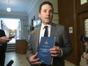 Quebec Justice Minister and French Language Minister Simon Jolin-Barrette holds up a book containing the 1867 Canadian constitution during a press conference Wednesday, June 8, 2022, at the Quebec City legislature.