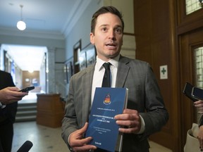Quebec Justice Minister and French Language Minister Simon Jolin-Barrette holds a book containing the 1867 Canadian constitution and the Canadian Act during a news conference, Wednesday, June 8, 2022 at the legislature in Quebec City.