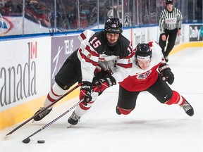 Canada's Shane Wright (15) and Austria's Tobias Sablattnig (12) battle for the puck at the IIHF World Junior Hockey Championship action in Edmonton on Dec. 28, 2021. The consensus choice for the No. 1 pick in the NHL draft this year is Wright of the Kingston Frontenacs, Jack Todd writes.