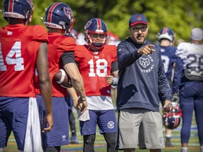 Alouettes quarterbacks coach Anthony Calvillo talks with Dominique Davis, left, Trevor Harris and Ben Holmes during training camp practice in Trois-Rivières on May 25, 2022.