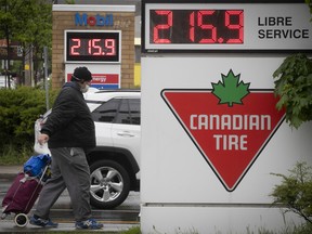A pedestrian walks by gas stations in Montreal on May 19, 2022 displaying a price of $2.15.9 per litre. According to the CAA-Quebec Gasoline Watch web page, the average price in Montreal Thursday July 14, 2022 at noon was $1.97.4.