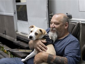 Guylain Levasseur and his puppy, Boris, stay cool in the shade of some trees next to the RV where is living, in Montreal on Tuesday, June 28, 2022.