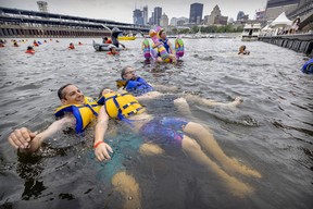 Dominique, left, Hugo and Daniel Leonard float in the water off Jacques-Cartier Pier in Montreal’s Old Port on July 1, 2022 as part of the Grand Splash.
