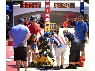 Organizers check on Ashley Scaletta of the Stonemills fire dept as she fails to complete the 6th and final task of dragging a 175-pound mannequin to safety during the Canadian Firefit Championships and picnic day, in Montreal, on Saturday, July 2, 2022.