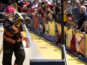 A crowd watches as Marc-André Gosselin of the Montreal fire department completes one of six stages during the Montreal firefighter's games and picnic day, in Montreal, on Saturday, July 2, 2022.