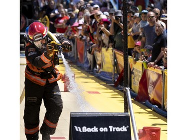 A crowd watches as Marc-Andre Gosselin of the Montreal fire dept complete one of 6 stages during the Canadian Firefit Championships games and picnic day, in Montreal, on Saturday, July 2, 2022.