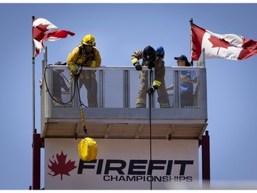 Elisabeth Bosse of College Montmorency takes an early lead in a 6 stage event during the Canadian Firefit Championships and picnic day, in Montreal, on Saturday, July 2, 2022. Firefighters must carry a large hose up several stories of stairs, then heave up another rope before moving on to the next stage.