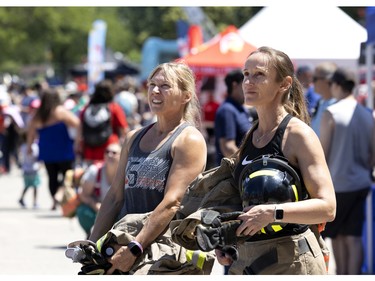 Lianne McAuley of the Stonemills fire dept, left, and Monica Hickey of the Pickering Nuclear fire dept watch the Montreal fire fighter's games as they wait for their heat, in Montreal, on Saturday, July 2, 2022.