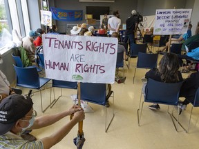 People hold signs at a protest event calling for social housing on Blue Bonnets land in Montreal on Tuesday, July 5, 2022.