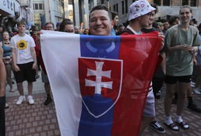 Benjamin Daydos holds up the Slovakian flag after the Montreal Canadiens announced Juraj Slafkovsky, a Slovakian, as the first pick in NHL Draft in Montreal Thursday, July 7, 2022. Other fans around him were more subdued, as many were hoping and expecting Shane Wright to be chosen.