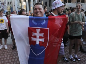 Benjamin Daydos holds up the Slovakian flag after the Montreal Canadiens announced Juraj Slafkovsky, a Slovak, as the top pick in the NHL Draft in Montreal on Thursday, July 7, 2022. Other fans around him were more subdued, as that many expected Shane Wright to be chosen