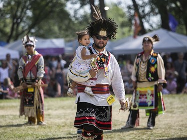 Clayton Rice, holding daughter Maiya Thompson, after an inter-tribal dance at the 30th edition of the Echoes of a Proud Nation Pow-Wow in Kahnawake on Sunday, July 10, 2022.
